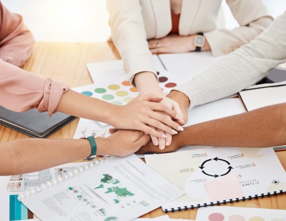 workers joining hands on a desk